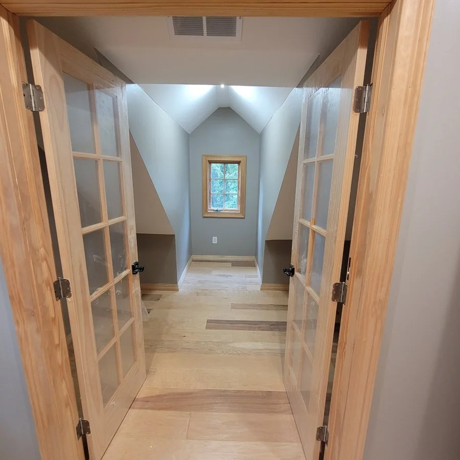 Boonton attic interior with wood French doors, light flooring, and a dormer window